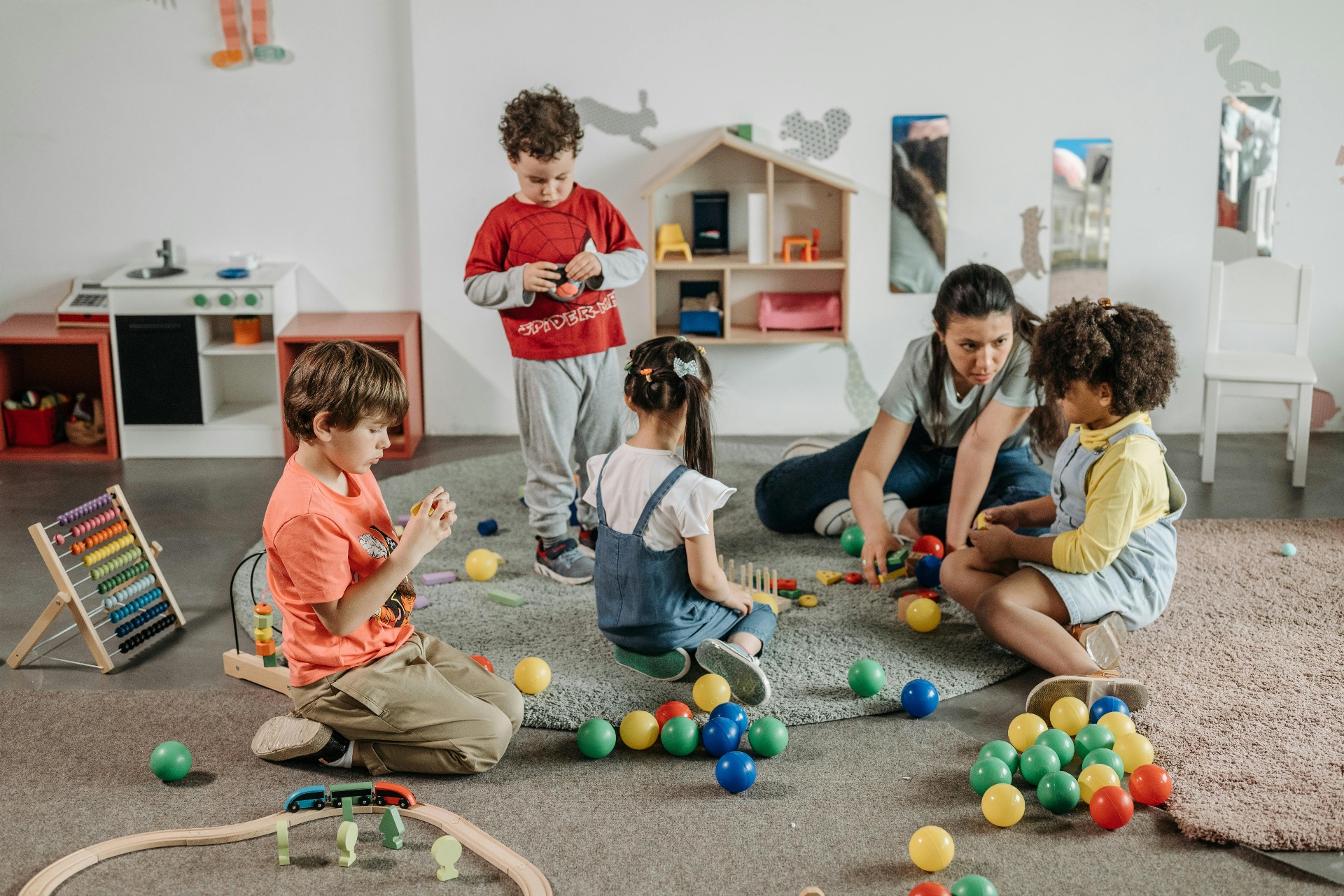 A caregiver and young children playing together in a colorful early learning space